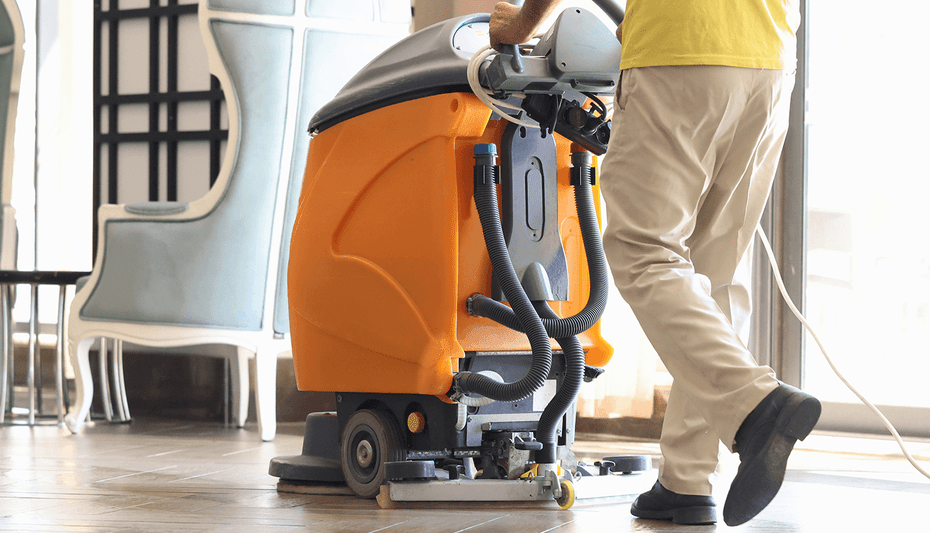 Janitor is cleaning hallway with washing vacuum cleaner